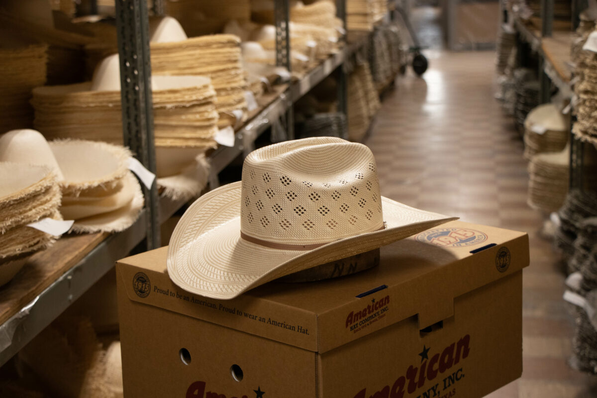 An American Hat Company straw hat is shown sitting on a hat box in the warehouse of American Hat Company.