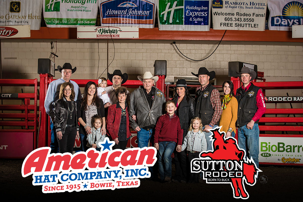 A large group of people are standing and smiling at the camera. The American Hat Company and Sutton Rodeo logos are overlaid along the bottom of the photo.